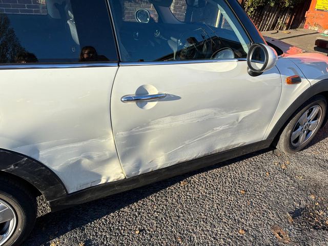White Mini Cooper with scraped and dented driver's door, before repair